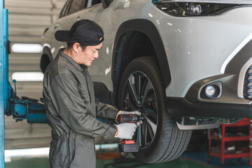 A male mechanic removing and replacing tires on a lifted car (tire change) 