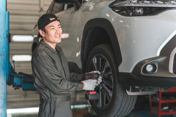 A male mechanic removing and replacing tires on a lifted car (tire change)  © buritora