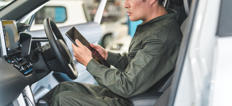 Male auto mechanic using a tablet device inside a car
