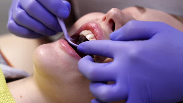 Close up of dentist examining patient front teeth using dental mirror. Professional oral checkup procedure in modern clinic. Concept of dental care, hygiene, and medical examination.