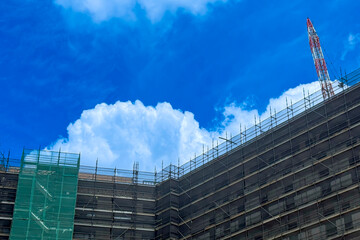 Photograph of a large white Cumulus cloud beginning to form over a multi storey tall building construction site in NSW, Australia.