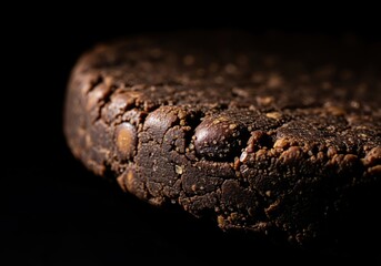 Fototapeta premium Extreme close up of a dark, textured fermented soybean disc with an uneven edge, low key lighting