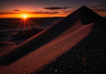 Epic sunset over dark coarse sand dunes, casting dramatic light and long shadows