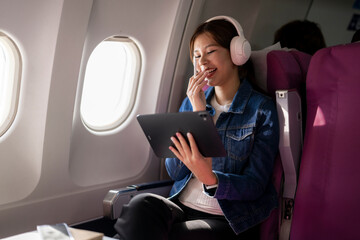 Woman watching content on tablet with headphones while flying in airplane
