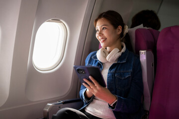 Fototapeta premium Woman enjoying travel on airplane looking through window