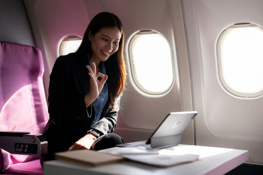 Asian businesswoman making video call gesture on airplane