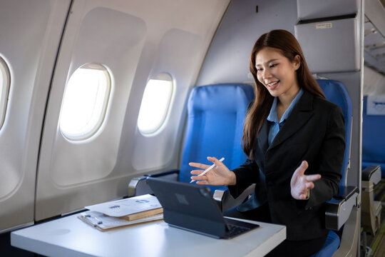 Businesswoman having video call on tablet during flight - Powered by Adobe