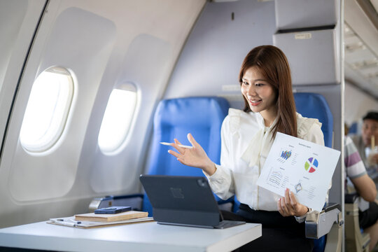 Young businesswoman on video call working during flight - Powered by Adobe