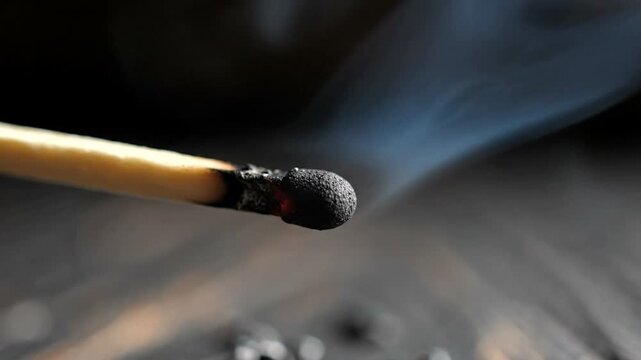 Close-up of a lit matchstick with smoke rising
