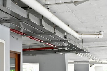 White and metal pipes running across a ceiling, part of an industrial or commercial infrastructure.