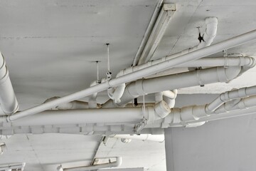 A network of white PVC pipes installed along a ceiling structure in a modern building.
