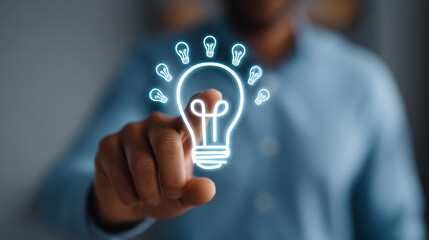 Innovative business concept with person pointing at glowing light bulb icons symbolizing ideas and creativity in blurred background