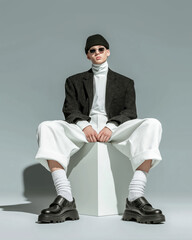 Fashionable Young Man Posing In White Corduroy Pants And Oversized Blazer With Beanie