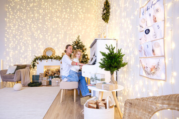 Caucasian woman and kid playing piano in living room on Christmas or New Year. Family holiday memory or celebration. Gift of music.