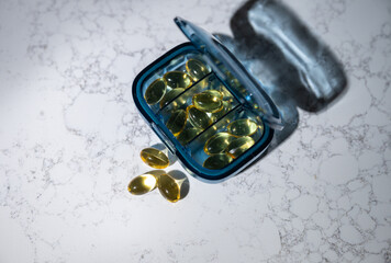Close up of Semi Clear Fish Oil Capsules in Blue Travel Pill Container