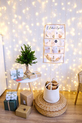 Cozy Christmas holiday scene with small fir tree, wrapped gifts, advent calendar and warm string lights. Winter celebration and seasonal decoration for home.