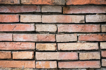 Close-up view of an old red brick wall with uneven and weathered bricks showing signs of age and wear