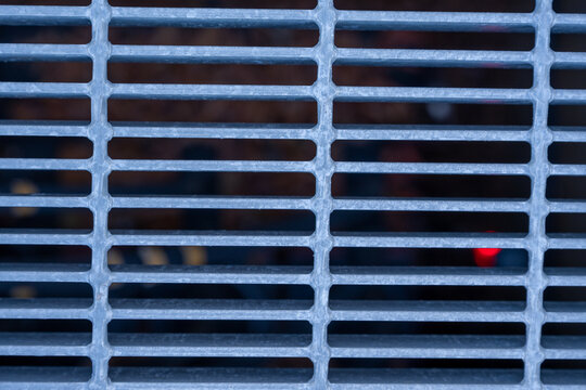 Close-up view of a metal grate with a repeating rectangular grid pattern in cool blue tones. Useful for industrial design, backgrounds, textures, and engineering themes.