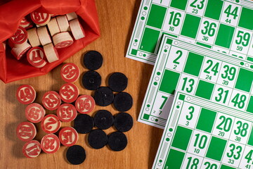 Community members enjoy a lively game of bingo with colorful cards and counting tokens on a wooden table during a fun evening gathering