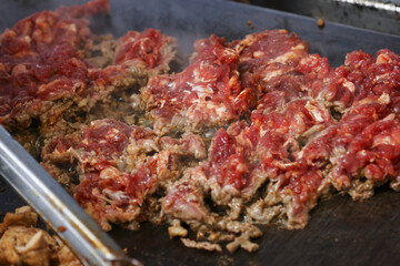 Savory chopped beef steak sizzling on hot griddle. delicious close up of meat grilling for an appetizing meal, showing food preparation for tasty lunch