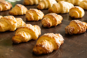 Freshly baked croissants cooling on a wooden surface in a sunny kitchen, showcasing golden color and flaky texture, inviting warmth and aroma of baked goods