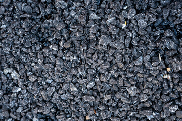 High-resolution close-up texture of dark gravel stones. Rough, natural rock surface ideal for use in design backgrounds, construction materials, textures, overlays, or product mockups.