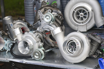 Close up of several metal turbochargers and engine parts on table. Automotive components for powerful car tuning, vehicle repair, and performance enhancement