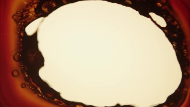 Abstract cinematic effect simulating a severe film burn or melt, starting with a yellowish-orange screen that rapidly develops a large, bright white circular shape surrounded by dark, bubbling, and fl