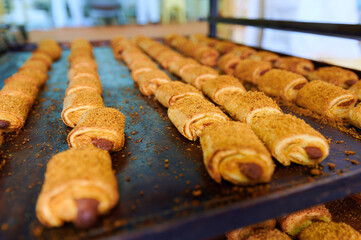Freshly baked rolled pastries with filling on a tray at a local bakery in the morning light