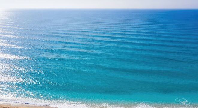 A serene blue ocean with gentle waves and a sandy beach.