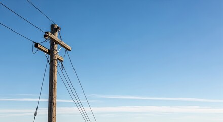 A wooden telephone pole with power lines against a clear blue sky.