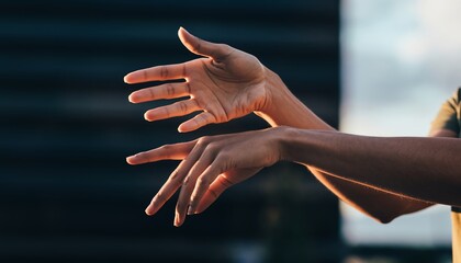 Two hands reaching out in warm sunlight against dark background.