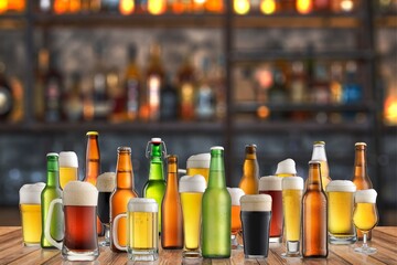 Assortment of various bottled and poured beers arranged on a wooden table, showcasing different styles and colors, ideal for bar themed projects and events.