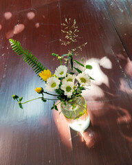 A beautiful flower arrangement in a glass vase casting a shadow on a wood surface