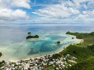 Village by the beach with turquoise lagoon and coral reef in clear tropical water. Siargao, Philippines. Sugba Blue Lagoon.