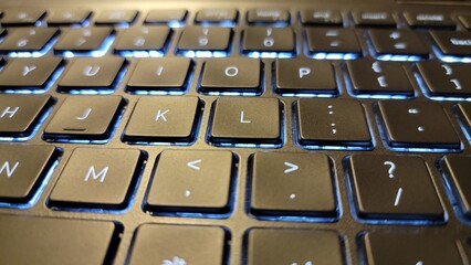 Closeup view of a laptop keyboard with illuminated blue backlighting