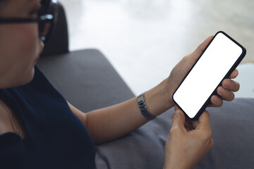 Cell phone blank white screen mockup. Woman hand holding, using mobile phone at home office, empty space for social media marketing, mobile app design, business technology