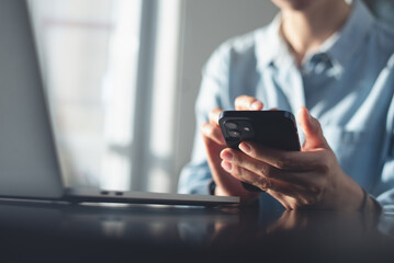 Close up, business woman using mobile smart phone during working on laptop computer at office,...
