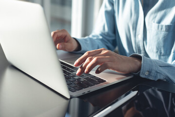 Close up, woman typing on laptop computer, surfing the internet on office table, online working. 