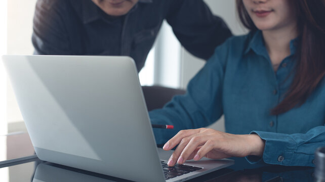 Two business person together working, analyzing business data on laptop computer at office. Startup business teamwork, colleague using laptop, meeting and sharing ideas, partnership, teamwork concept