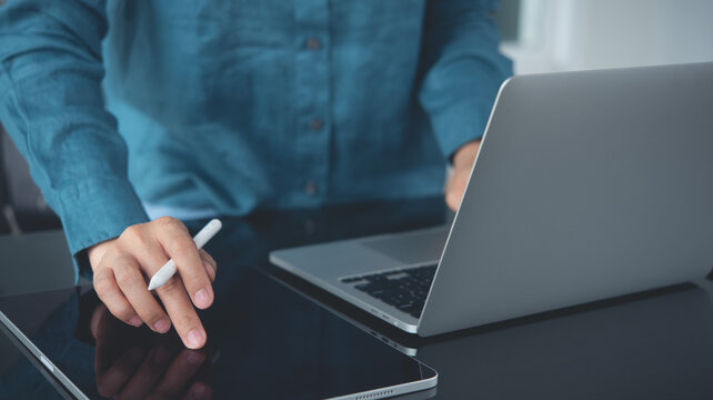 Woman using digital tablet and working on laptop computer on table office, close up. 