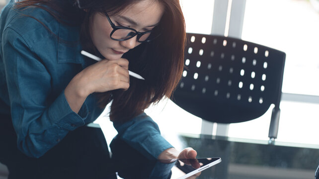 Business woman using digital tablet, reading and proofing business document, working at modern office. 