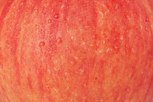 Apple with water drops macro photo as background.