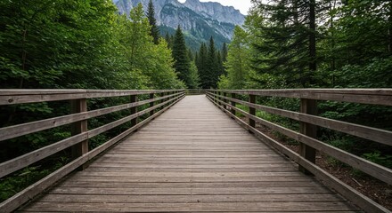 Obraz premium Pathway to Nature's Embrace: An inviting wooden bridge leads the eye towards a majestic mountain range, enveloped by lush forest, showcasing the serenity of nature.