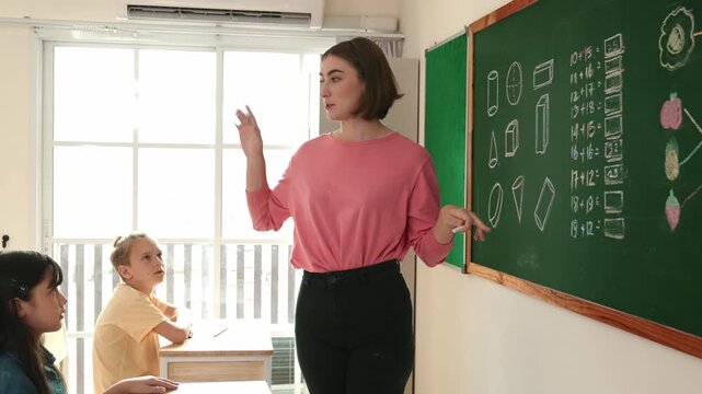 Caucasian teacher request student to raise hand up to answer question at in front of classroom. Attractive instructor calling children for writing answer in math lesson at elementary school. Pedagogy.