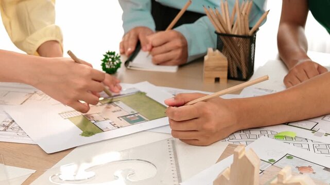 Smart architect and safety engineer discussion about building blueprint on table with architectural document, measurement tools and wooden block scatter around at modern office. Closeup. Delineation.