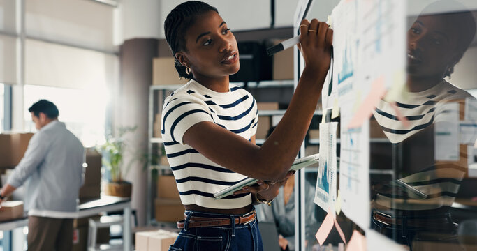 Woman, writing or brainstorming with tablet at glass wall for ecommerce, logistics or shipping stats. Female person, notes and board in office with tech, supply chain strategy of distribution graphs.