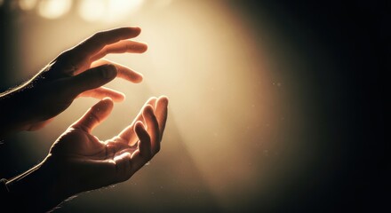 Close-up shot of cupped hands reaching towards a bright light source with a dark background and warm tones.