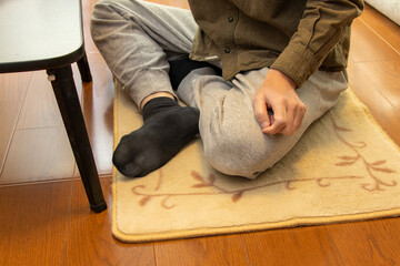 床に敷いたカーペットの上であぐらを掻く男性