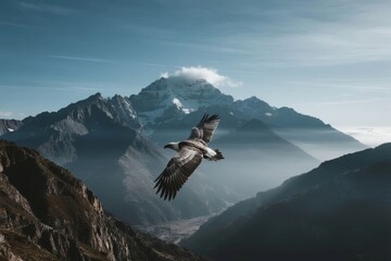 A bird of prey soars over a majestic mountain range with snow-capped peaks and misty valleys under a clear blue sky.